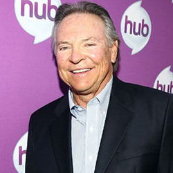 Frank Welker wearing a black suit on a light blue colored shirt smiling